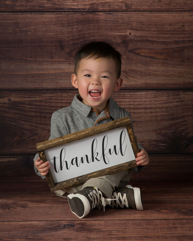 Preschool Photography ideas - Preschool boy sitting down holding a sign that says thankful, on rustic background