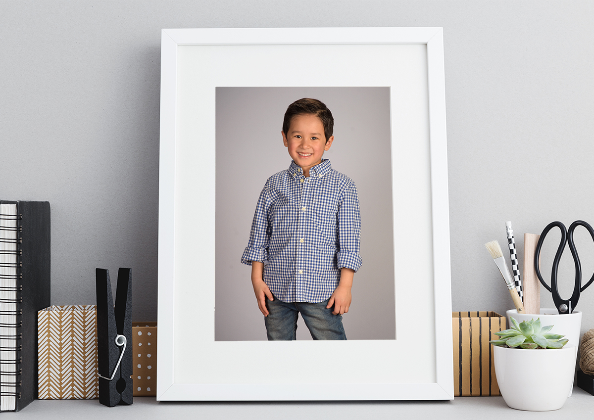 White picture frame sitting on a desk with preschool photo inside.