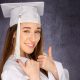 Senior picture of girl in white cap and gown on a gray background