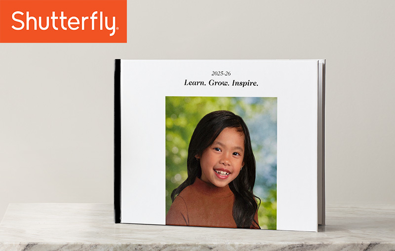 White frame sitting on a desk with child's school photo inside frame.